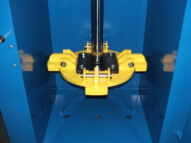 Blue industrial drum crusher with yellow pressing mechanism for waste management.