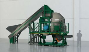 Industrial waste processing hammer mill with conveyor system in a factory setting.