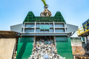 Industrial waste shredder processing recyclables at waste management facility.