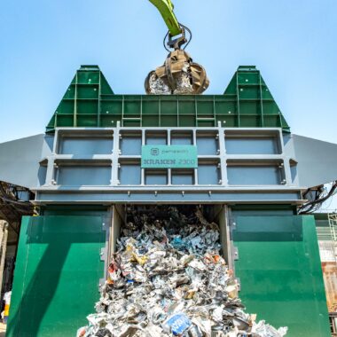 Industrial waste shredder processing recyclables at waste management facility.