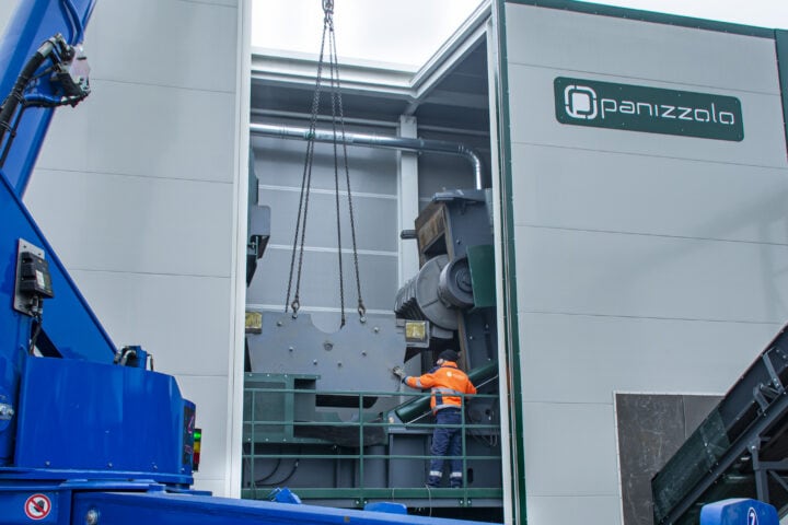 Large industrial hammer mill in operation at waste processing facility.