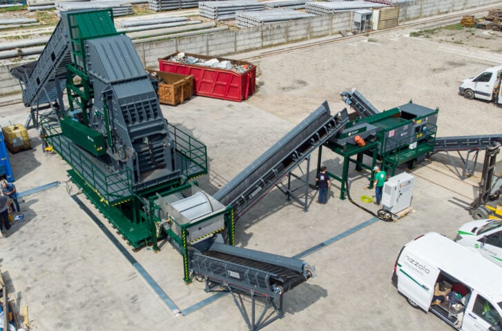 Industrial waste processing hammer mill with conveyor and control panel.
