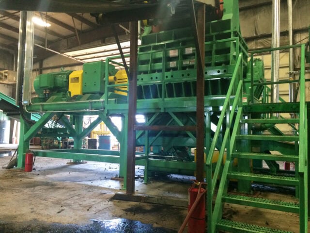 Green waste grinder and granulator machinery in industrial facility.