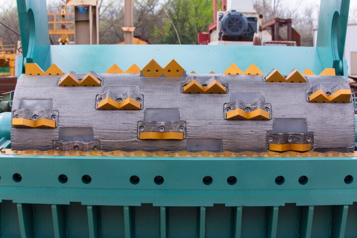 Close-up of tyre grinder blades and rollers for waste recycling.