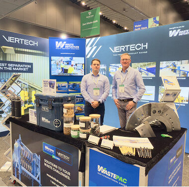 Two Waste Initiatives specialists at booth showcasing recycling equipment and containers.